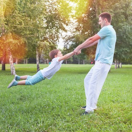 60249322 - dad turns child holding hands outdoor. family. father spinning his son. happy funny people. summer. emotions. childhood