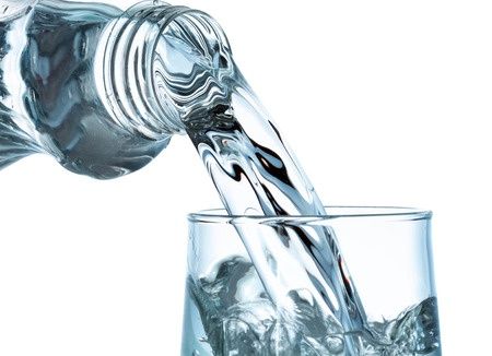 41457484 - pouring water from bottle into glass on white background